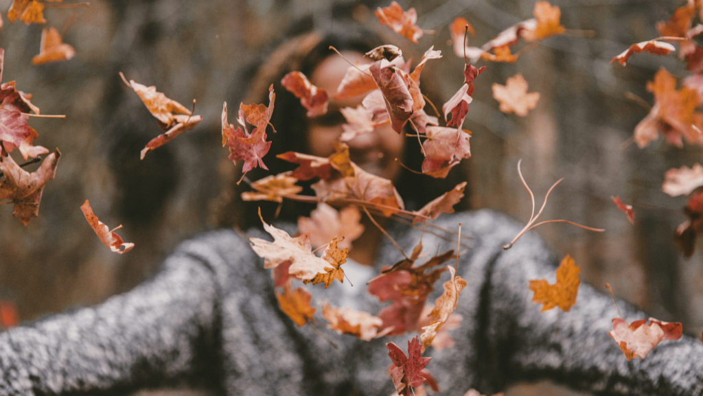 Woman throwing fall leaves